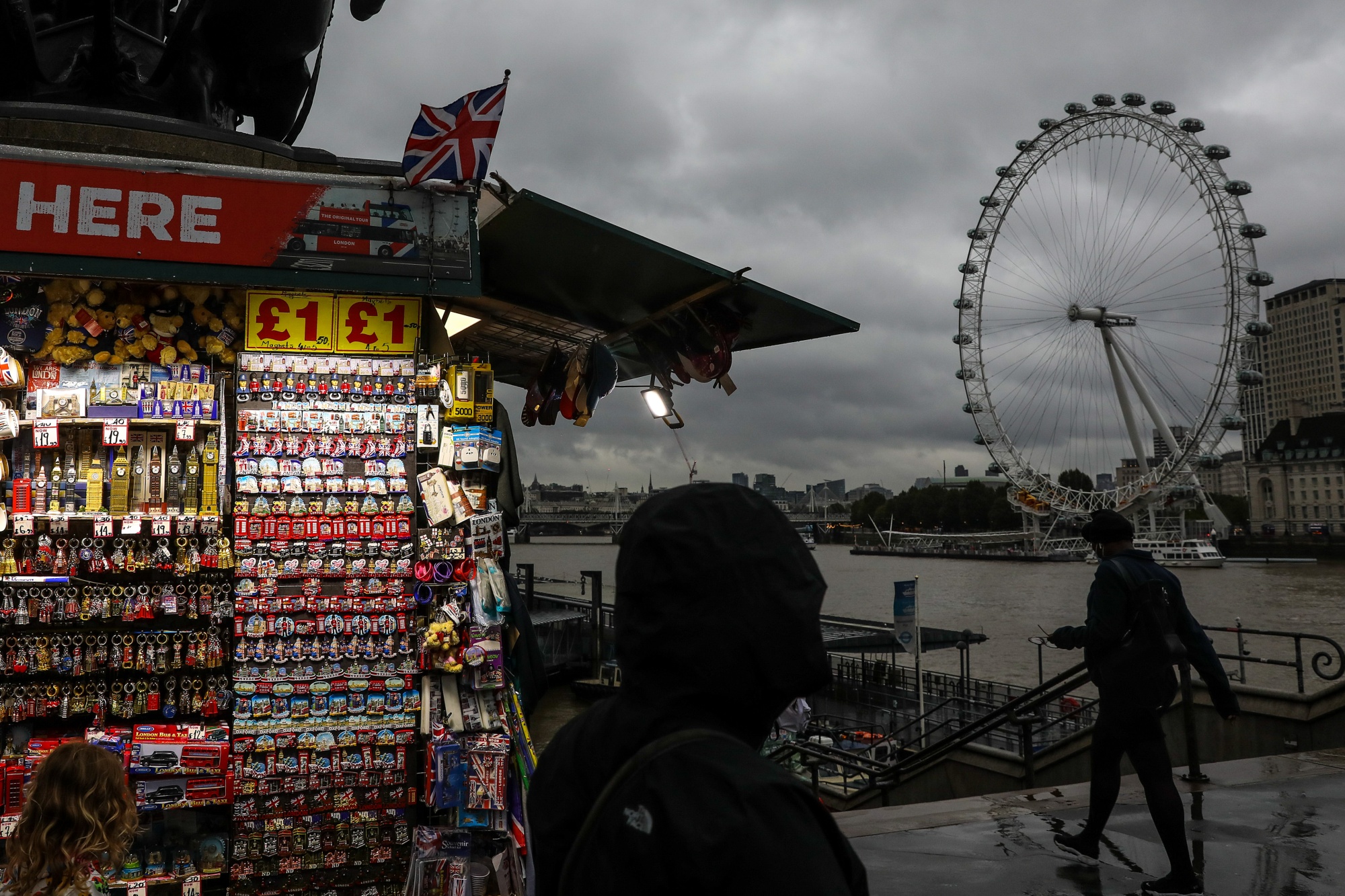 Pedestrians walk past a tourist souvenir stall on Westminster Bridge in London.