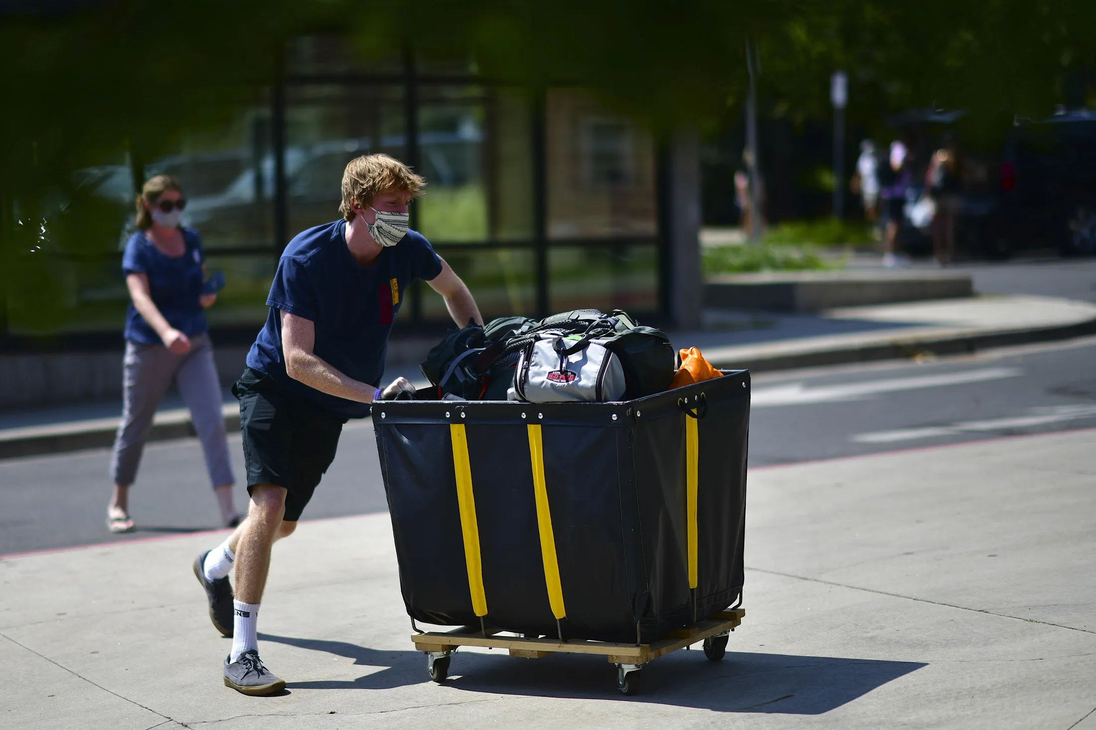 An incoming freshman wearing a protective mask moves into a campus.