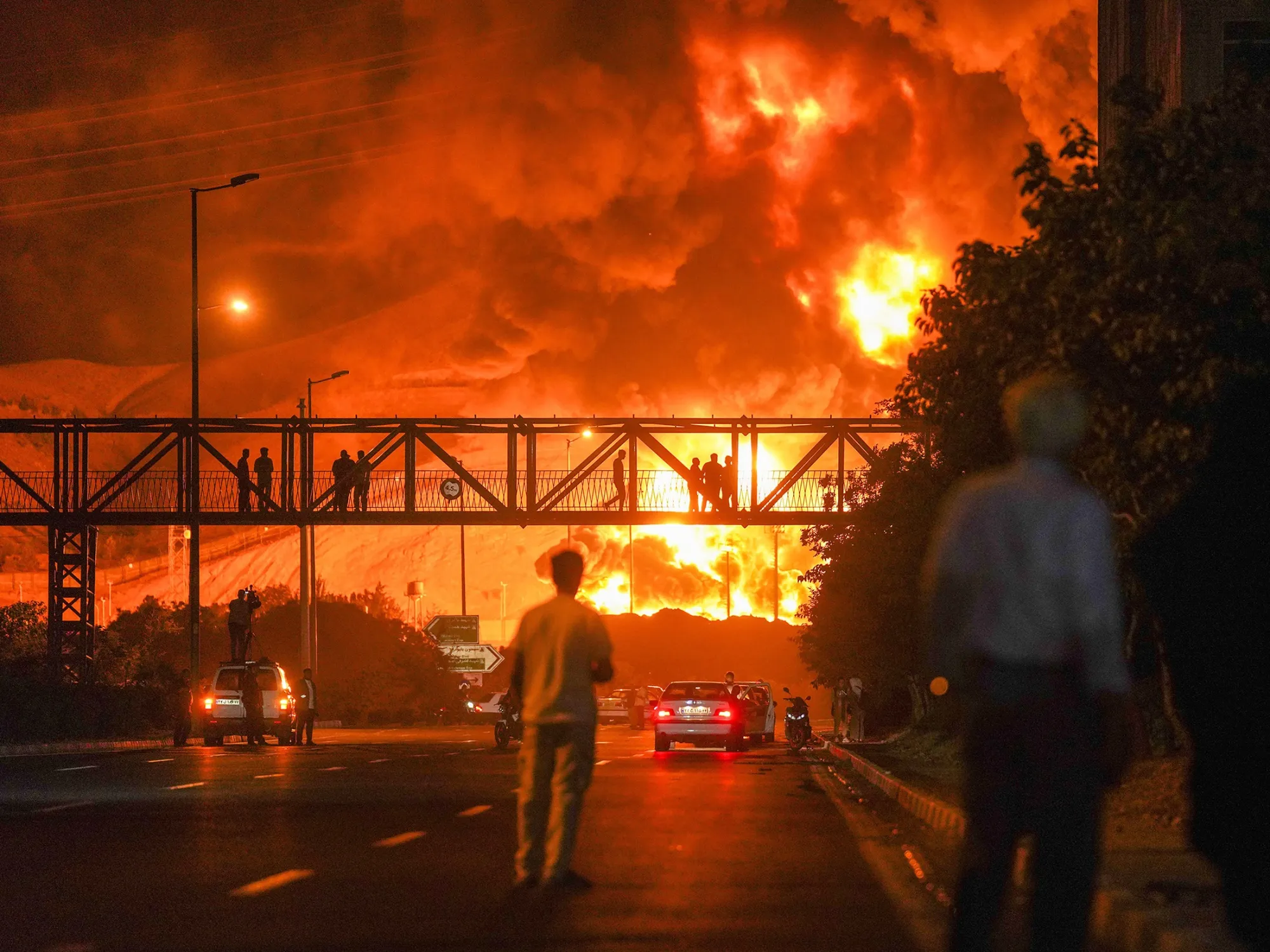 Iranians watch a plume of heavy smoke and fire rise from an oil refinery in Tehran&nbsp;after it was hit in an overnight Israeli strike on June 15.
