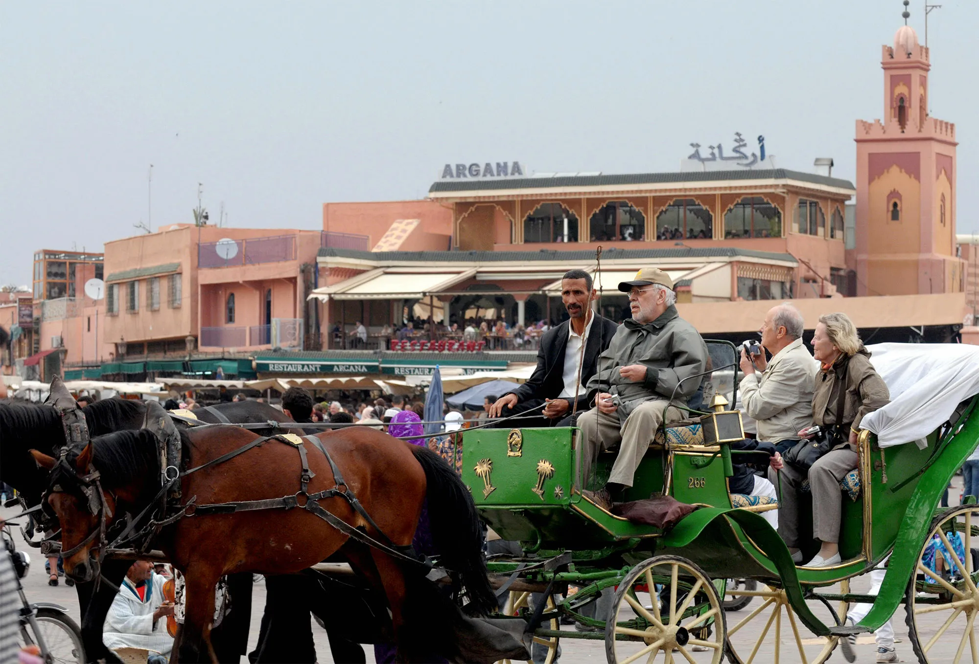 Tourists sit in a horse-drawn carriage next to the mosque Koutoubia in Marrakech.