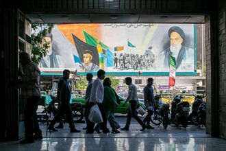 People pass a billboard depicting former Iranian supreme leaders in Tehran, on May 9.