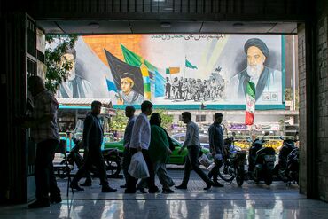 People pass a billboard depicting former Iranian supreme leaders in Tehran, on May 9.