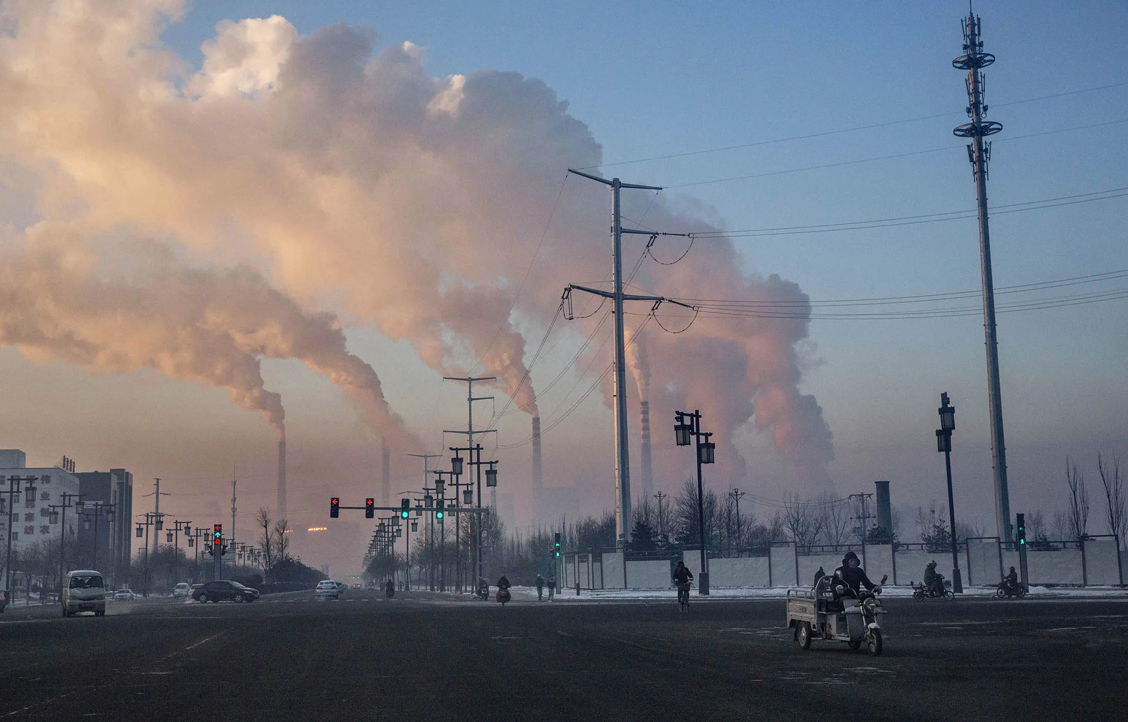 Chinese workers commute as smoke billows from a coal fired power plant in Shanxi.
