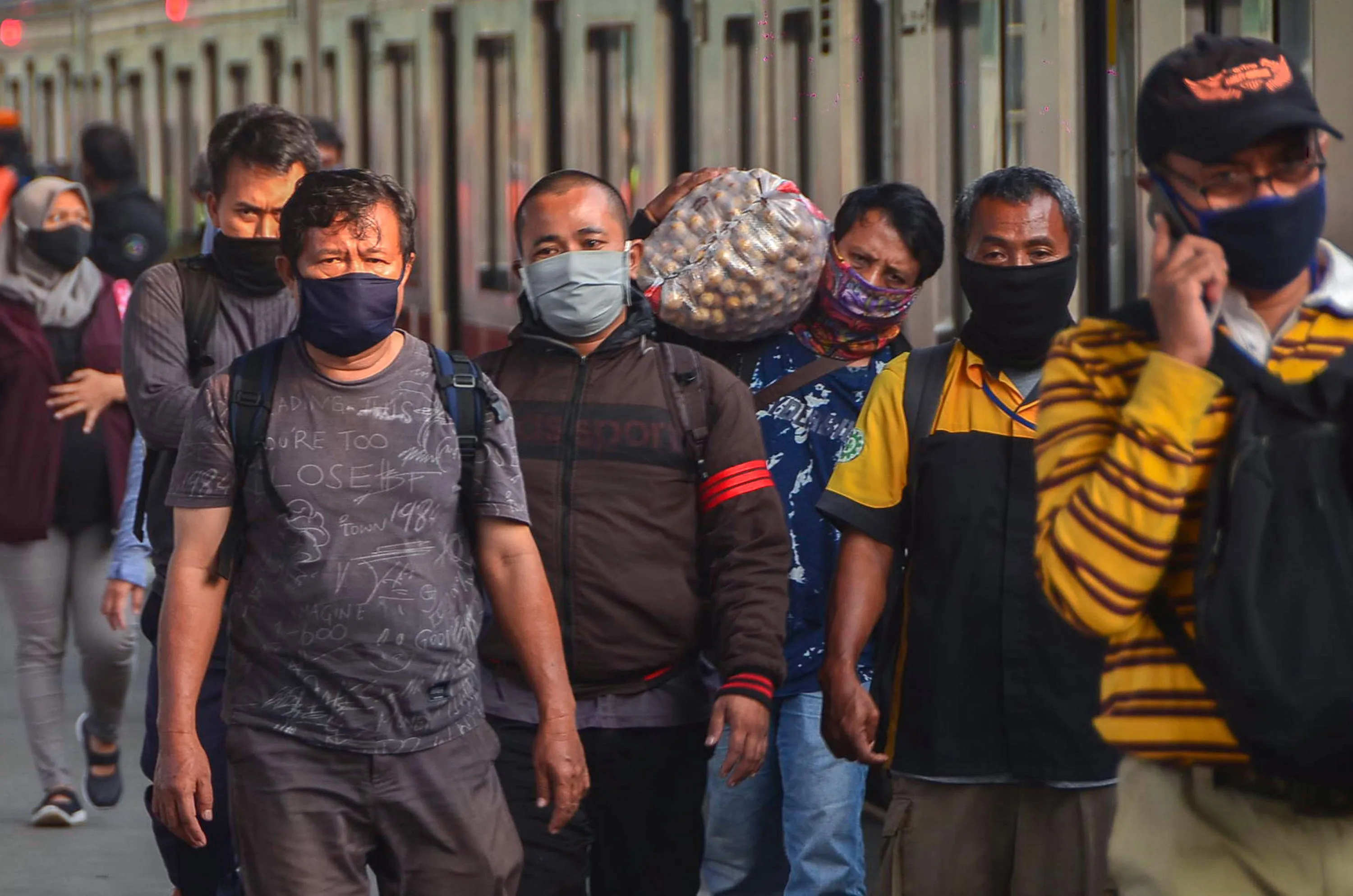 Commuters wearing face masks amid concerns over the COVID-19 coronavirus walk at a train staiton in Bekasi, on April 15.&nbsp;