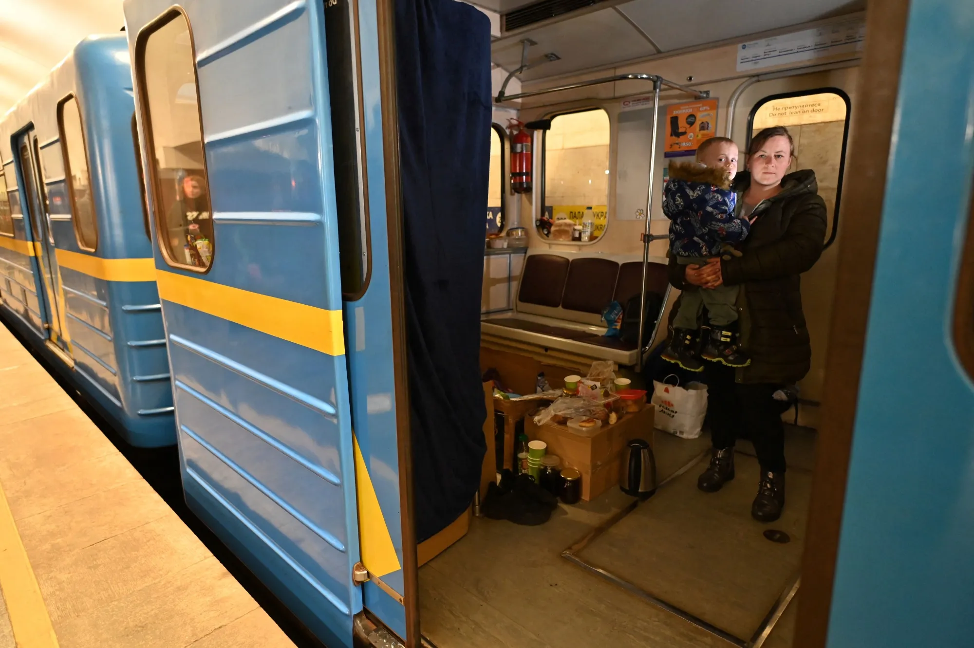 A woman holds her child inside a subway car in an underground metro station used as a bomb shelter in Kyiv on March 13.