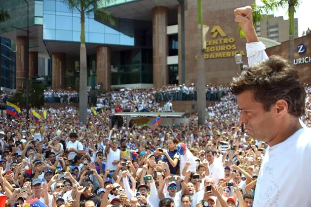 Leopoldo Lopez, an ardent opponent of Venezuela's socialist government facing an arrest warrant, surrounded by supporters in Caracas on Feb. 18