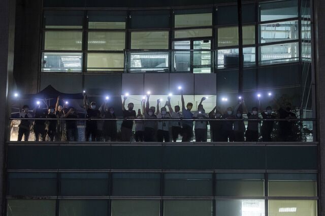 Workers illuminate mobile phone torches from a balcony at the headquarters of the Apple Daily newspaper and its publisher Next Digital Ltd. in Hong Kong, China, on Wednesday, June 23, 2021. Hong Kong’s pro-democracy Apple Daily newspaper, which cheered on the city’s anti-China protest movement in 2019, is shutting down after authorities used a national security law to arrest its top editors and freeze company assets.