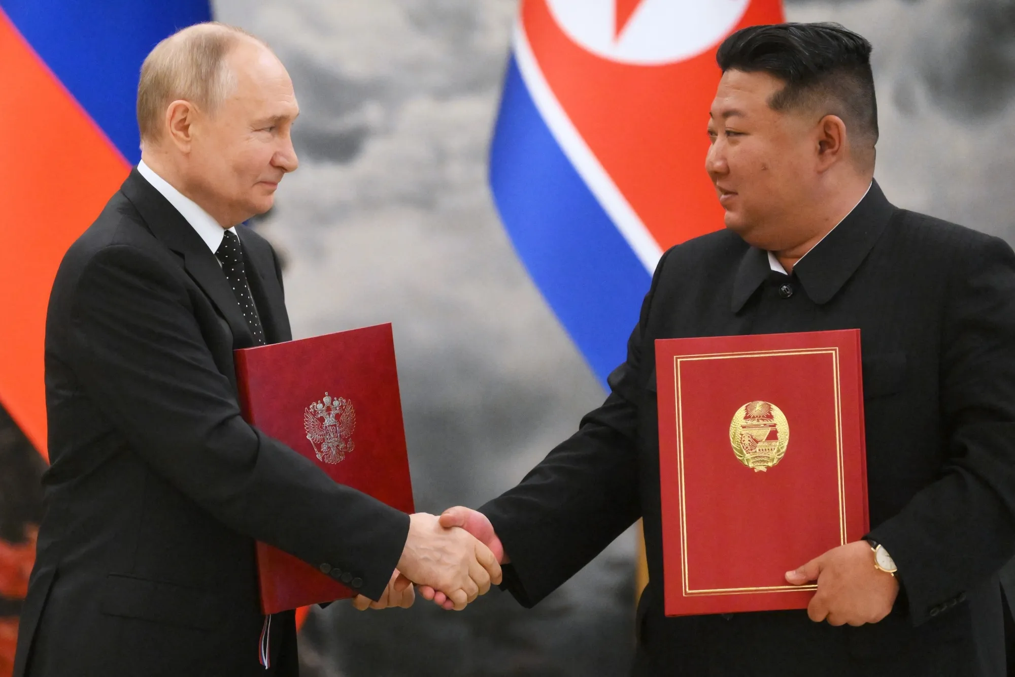 In this pool photograph distributed by the Russian state agency Sputnik, Vladimir Putin shakes hands with Kim Jong Un after a signing ceremony at Kumsusan state residence in Pyongyang, on June 19.
