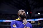 Los Angeles Lakers forward LeBron James peers at the American flag during the national anthem prior to the start of an NBA basketball game in Dallas, Sunday, Dec. 25, 2022. (AP Photo/Emil T. Lippe)