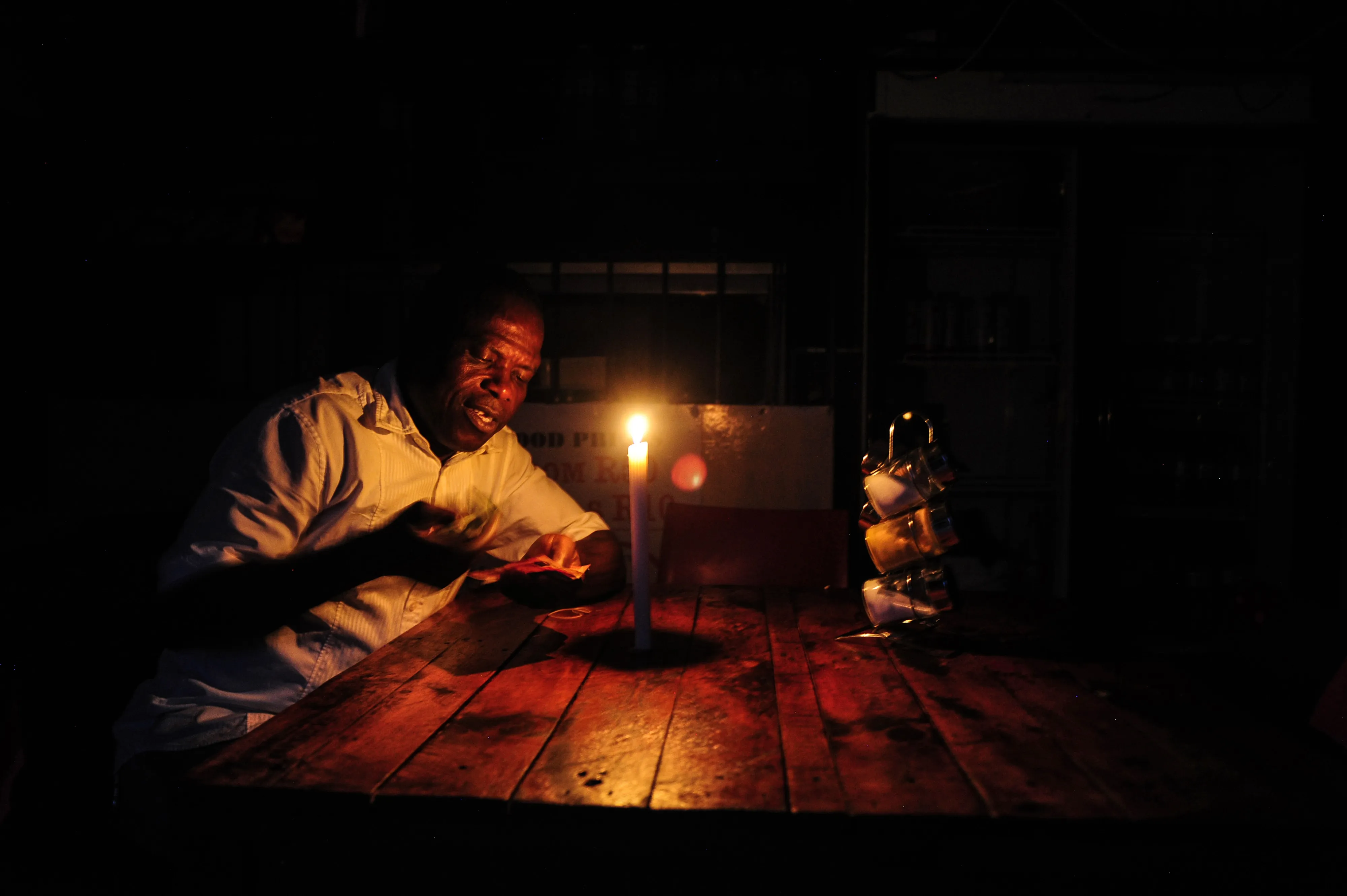 A restaurant owner counts cash by candlelight during a load shedding power outage&nbsp;in Johannesburg, South Africa, on Feb. 13.&nbsp;