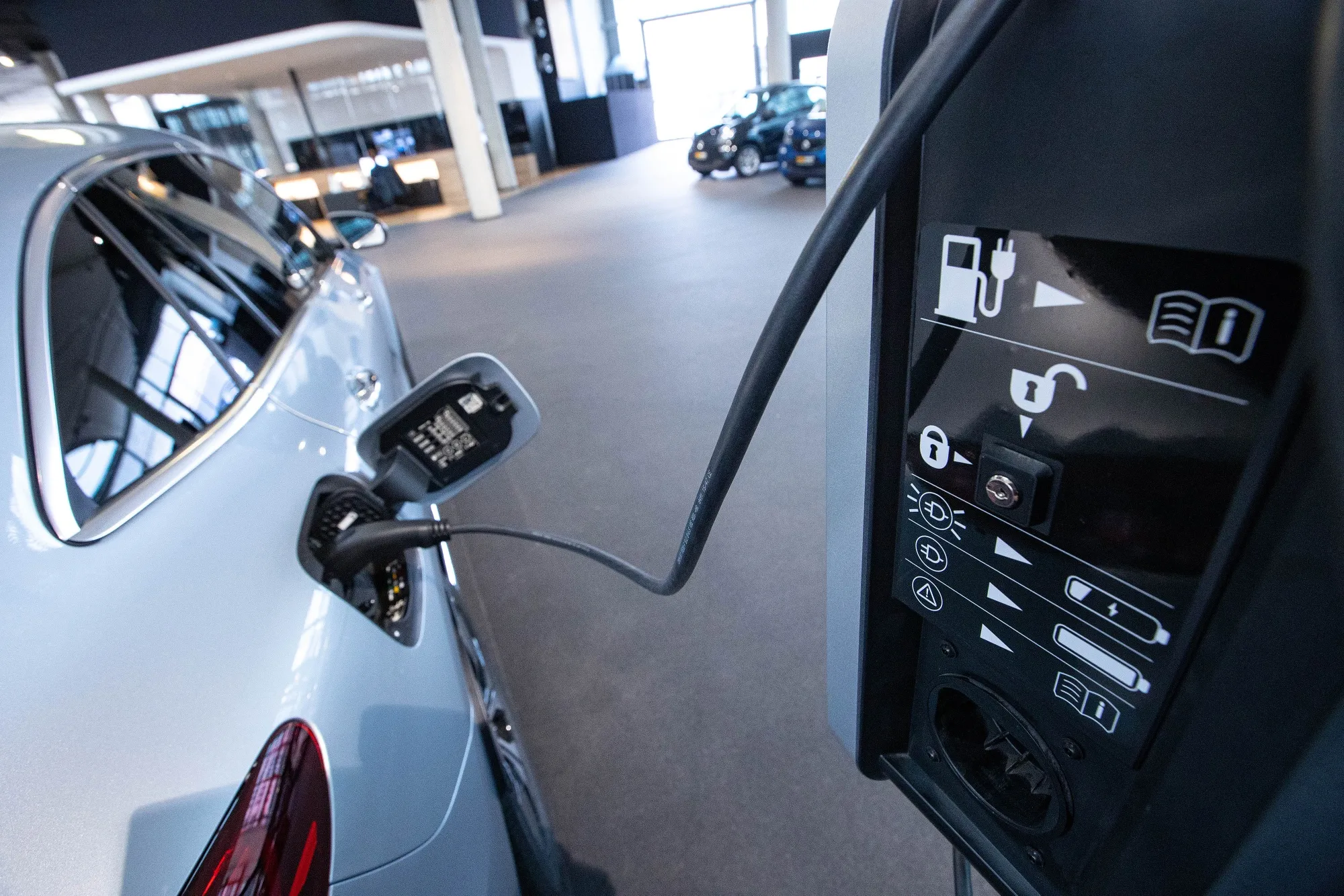A Mercedes-Benz EQC electric vehicle connected to a charger inside a showroom in Berlin.