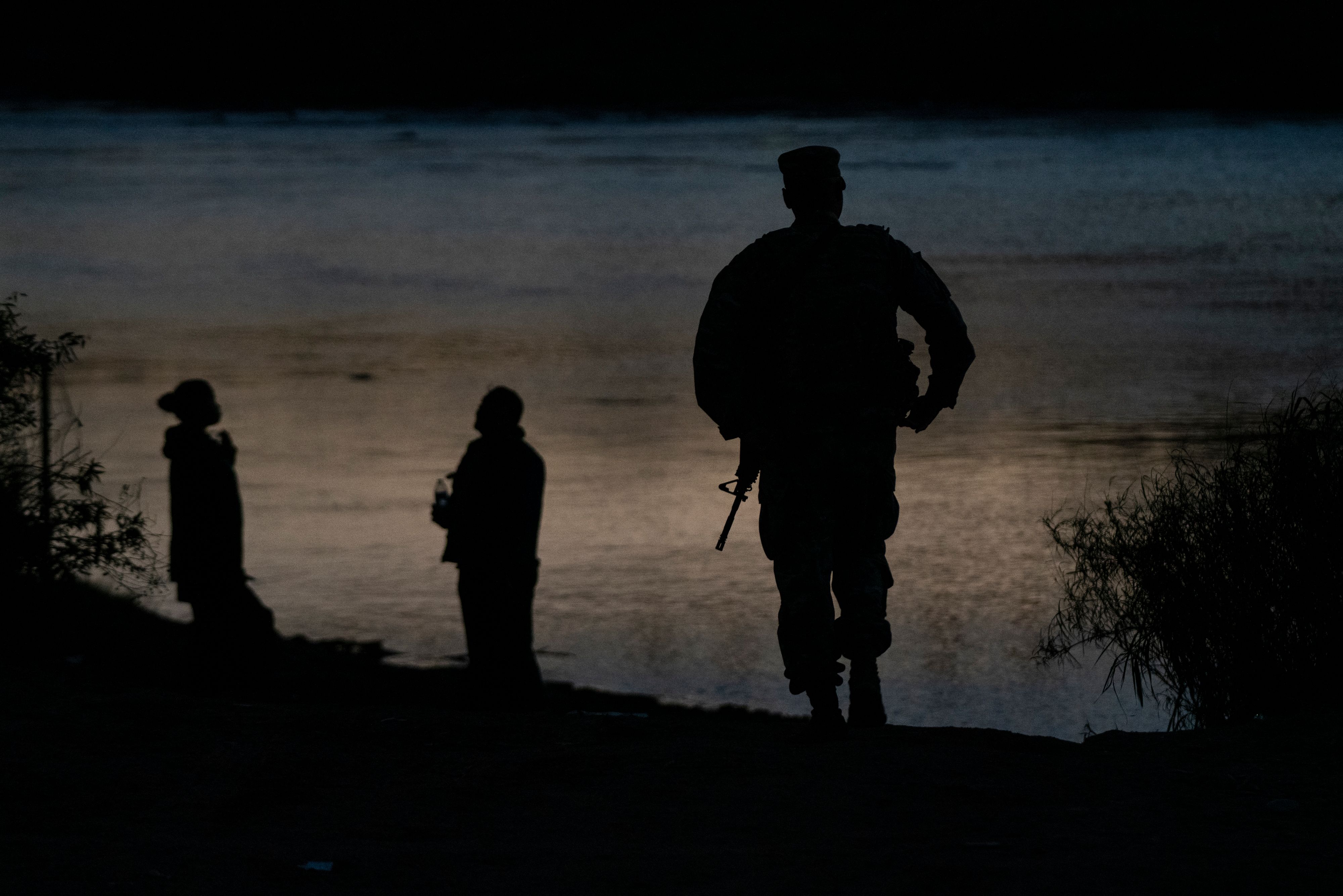 Migrants&nbsp;wait as a member of the National Guard walks towards them in Eagle Pass, Texas.