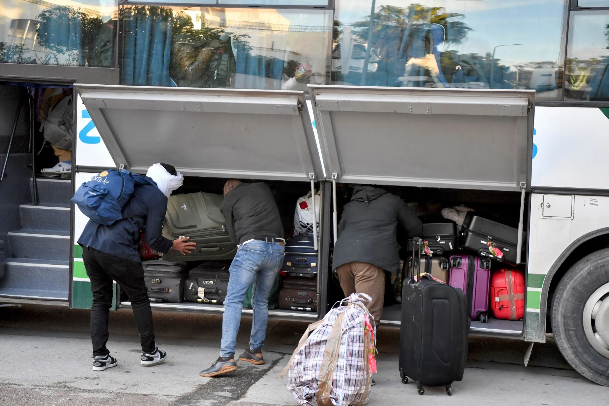 Sub-Saharan migrants load their belongings onto a bus as they head to a repatriation flight, leaving Tunis, for their countries of origin on March 4.
