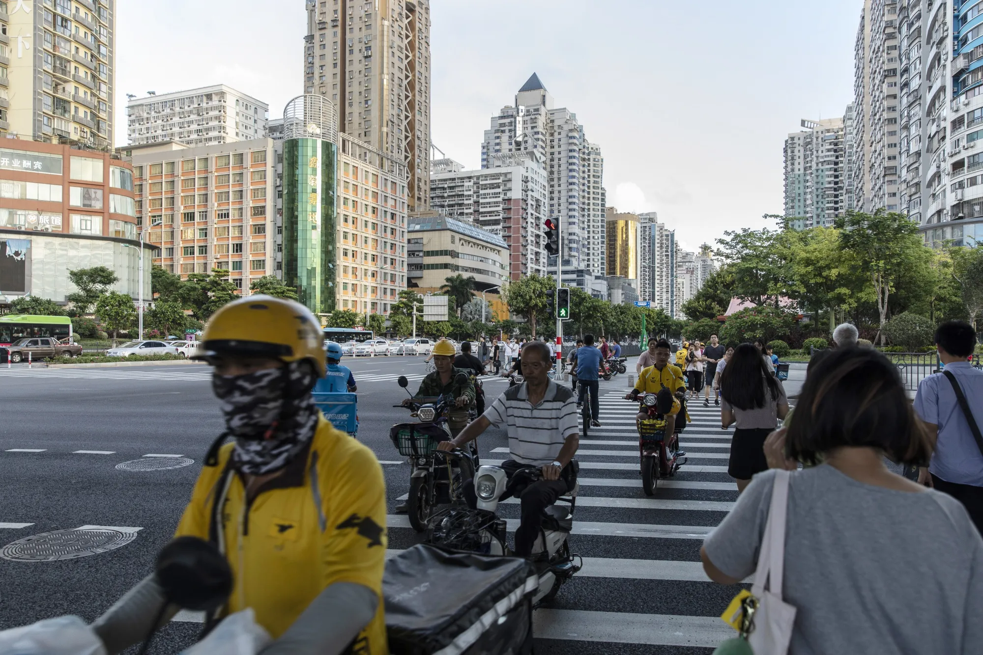 Pedestrians and motorcyclists cross a road in Xiamen.