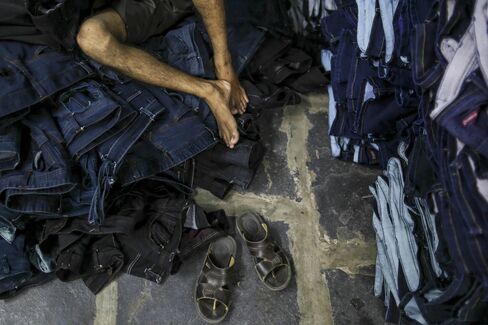 A laborer lies on pile of denim jeans during a break at Aditya jeans washers in Ballari.