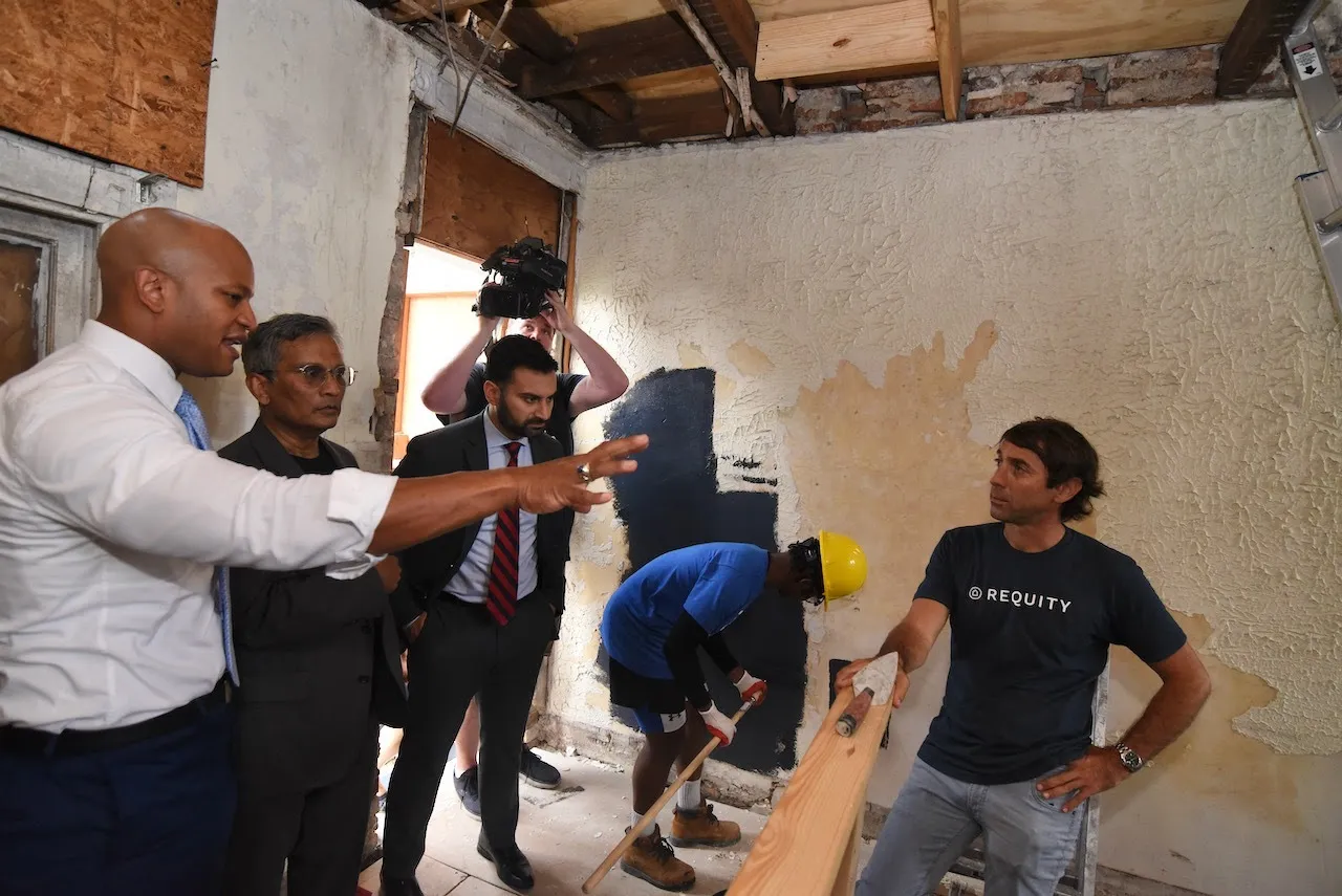 Maryland Governor Wes Moore (left) and White House National&nbsp;Climate Advisor&nbsp;Ali Zaidi&nbsp;(center) tour a project by Requity, a nonprofit that trains students to perform zero-energy building renovations in West Baltimore.