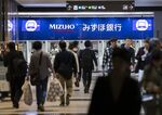 Pedestrians walk in front of Mizuho Bank Ltd. automated teller machines (ATMs).