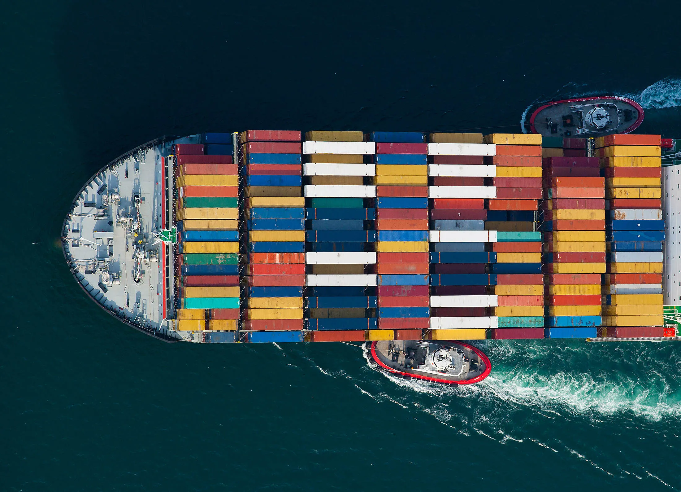 Tugboats help guide a container ship approaching the Port of Long Beach in Long Beach, California, U.S.
