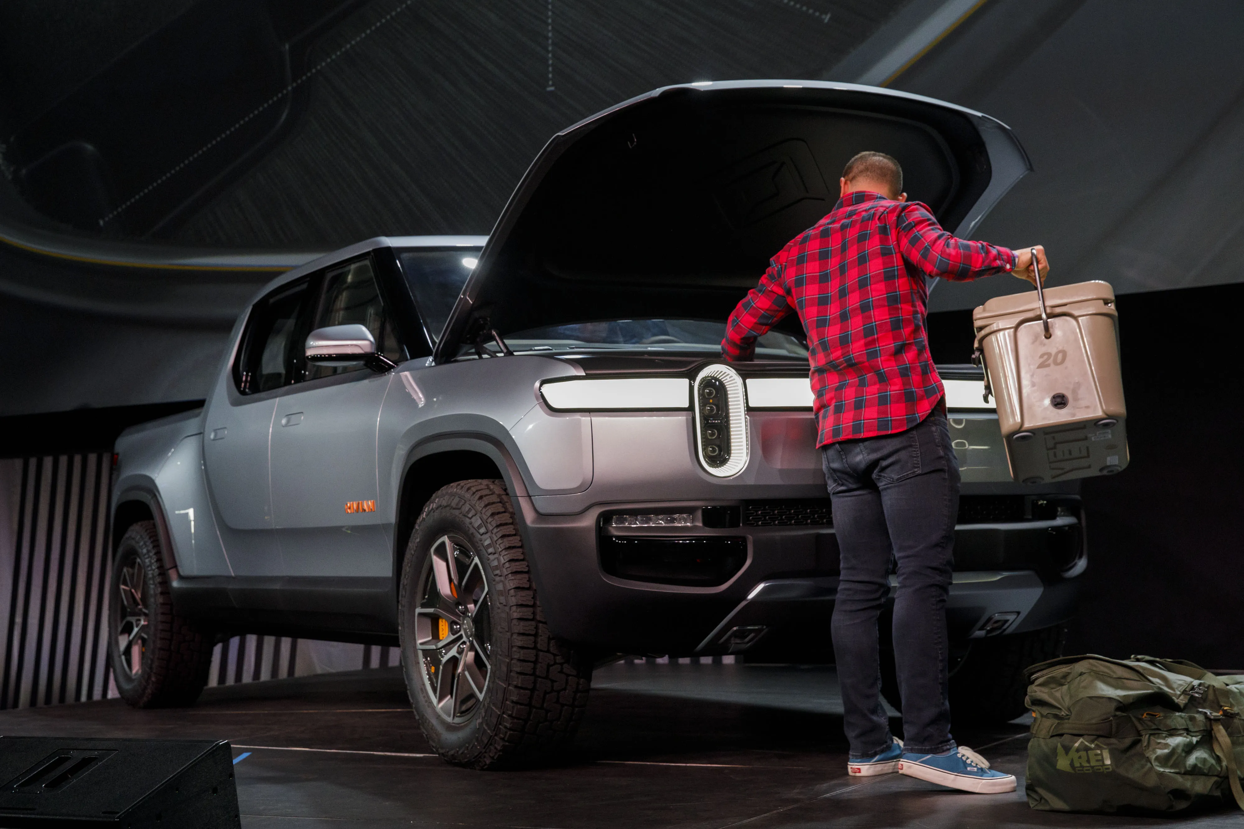 A person places items into the front trunk cargo area of the Rivian Automotive Inc R1T electric pickup truck.