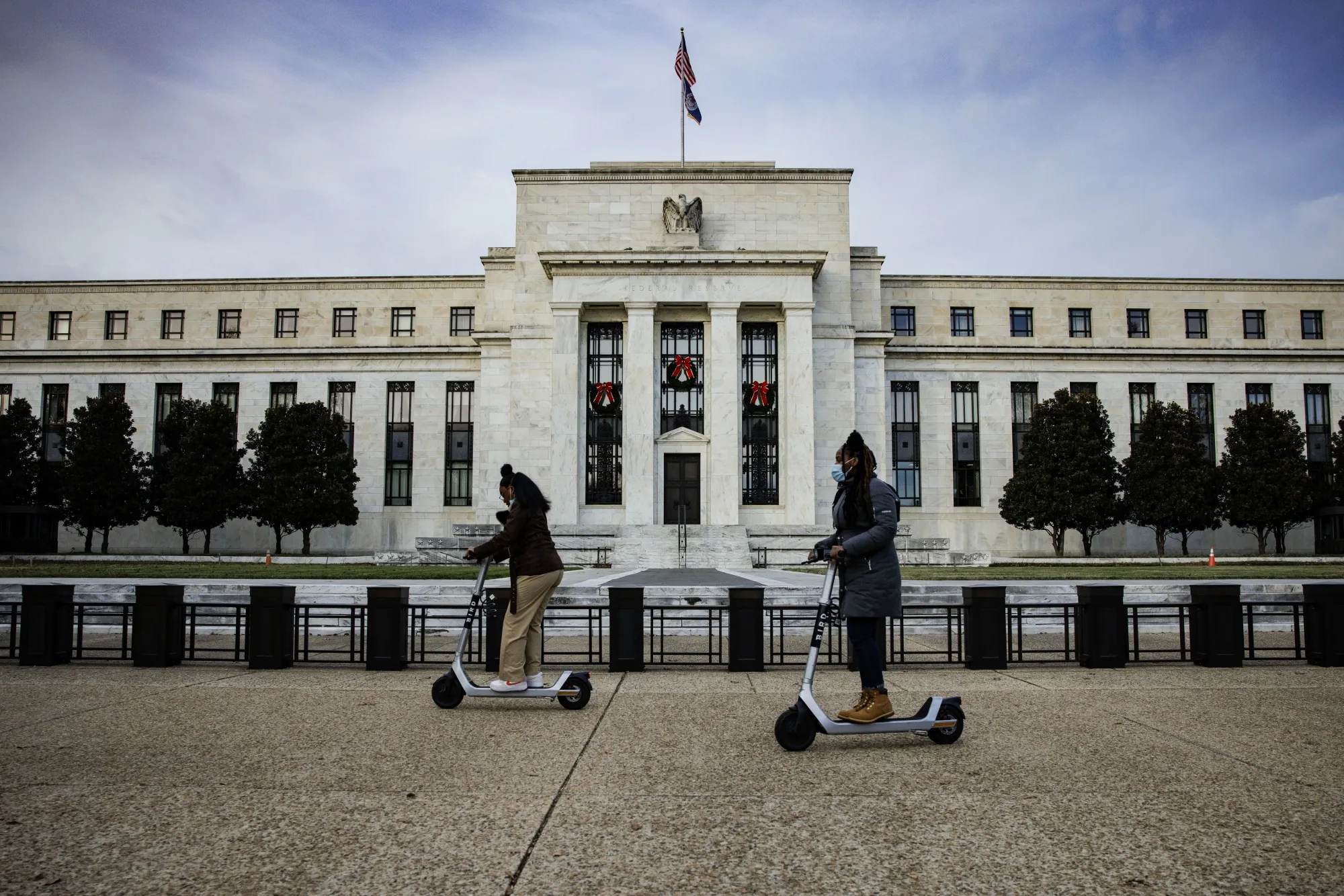 Visitors ride electric scooters past the Marriner S. Eccles Federal Reserve building.