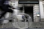 A cyclist rides pasts a security guard standing outside the Bank of Japan (BOJ) headquarters in Tokyo.
