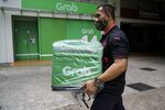 A man collects gear for a delivery driver at GrabFood, Grab Holdings Inc.'s online food-delivery platform, outside the company's office in Singapore.