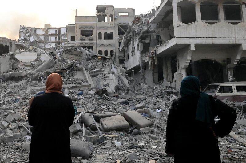 Two Palestinian women look at destruction following Israeli airstrikes on Gaza City on October 10.