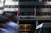 A pedestrian walks past American flags flying at BlackRock Inc. headquarters in New York, U.S.