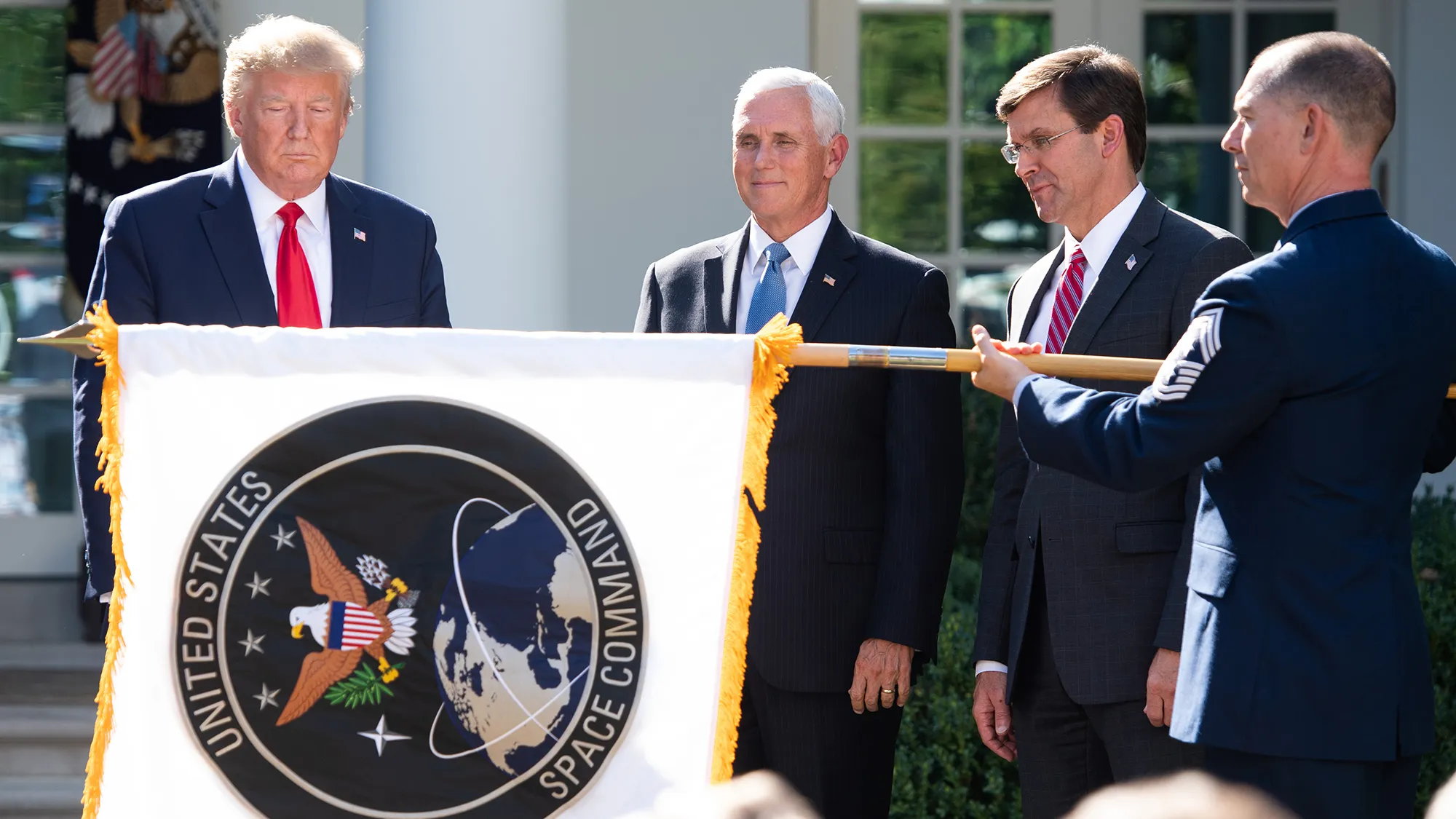A member of the military unfurls the new U.S. Space Command flag alongside Donald Trump and Mike Pence at the White House in Washington on Aug. 29.