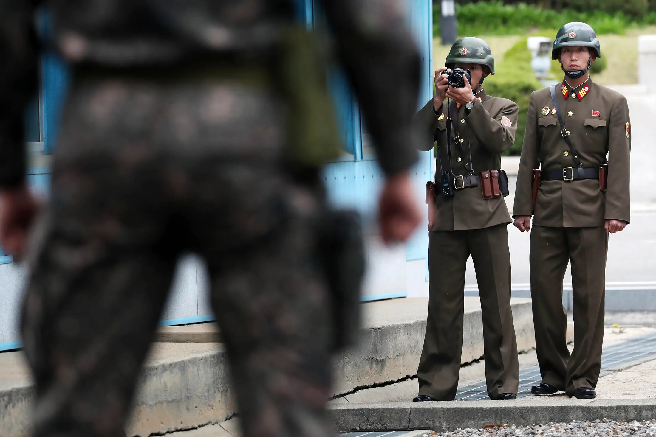 A North Korean soldier takes a photograph, background, as a South Korean soldier, foreground, stands guard at the truce village of Panmunjom in the Demilitarized Zone in Paju, South Korea, on April 17, 2017.
