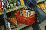 A shopper holds a shopping basket with groceries inside a store.