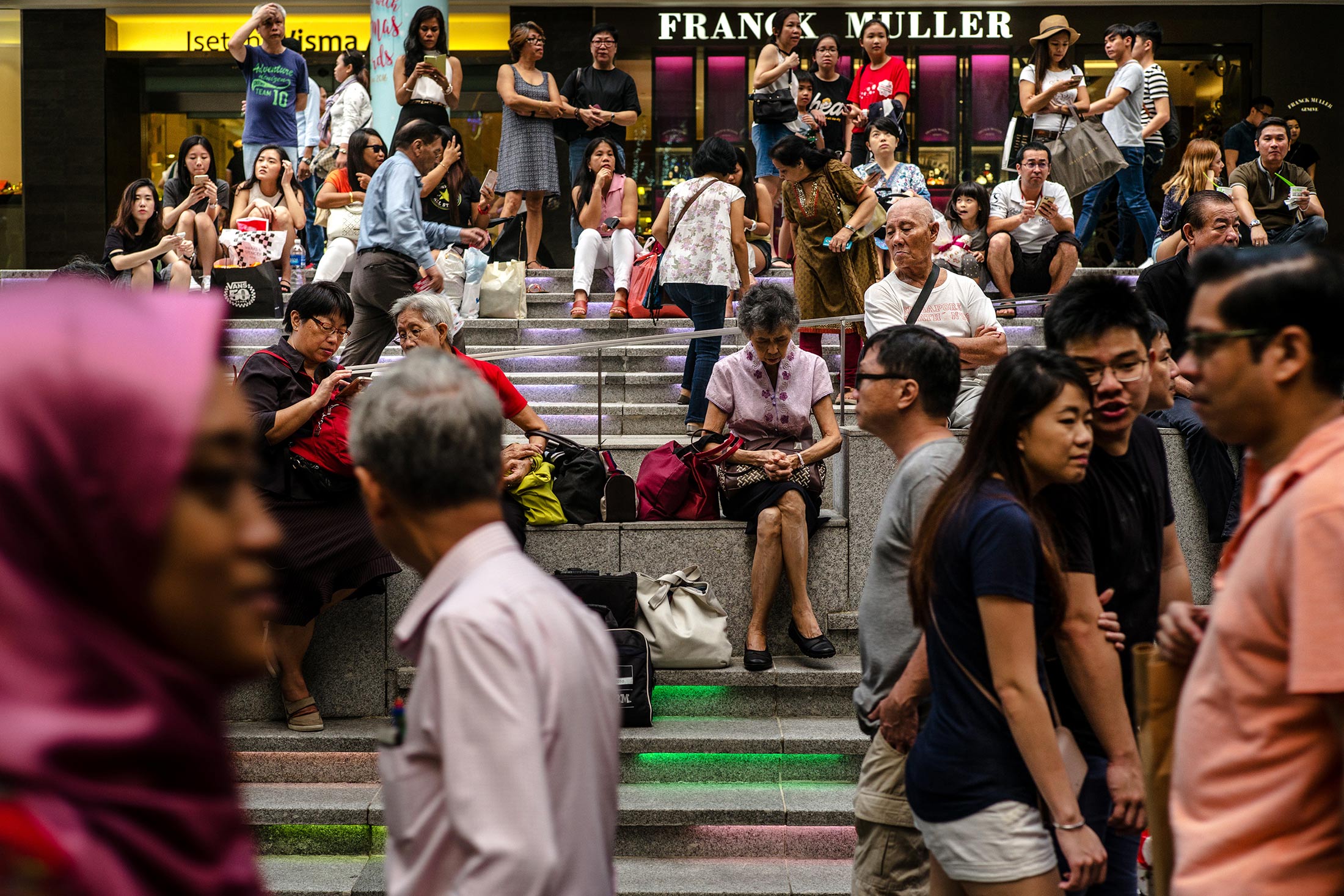 People sit on a set of steps on Orchard Road in Singapore, on Sunday, Dec. 16, 2016.
