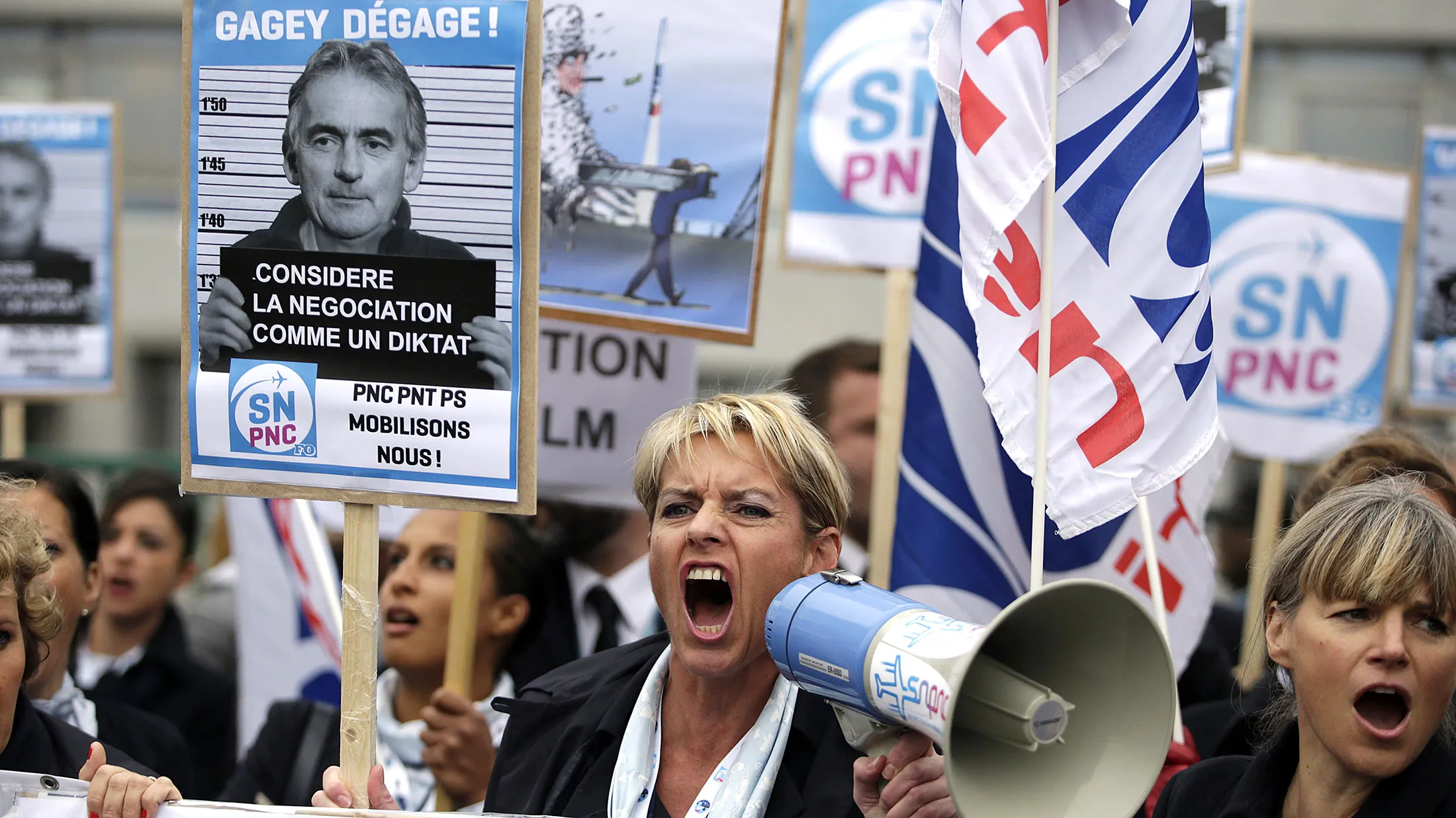 Employees of Air France shout slogans and hold placard reading 'Gagey get away!', during a demonstration in front of the company headquarters, during the launch of the plan at a central committee meeting, in Roissy-en-France, on Oct. 5, 2015.
