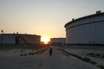 An employee walks past crude oil storage tanks at Saudi Aramco's Ras Tanura oil refinery and terminal in Ras Tanura, Saudi Arabia.