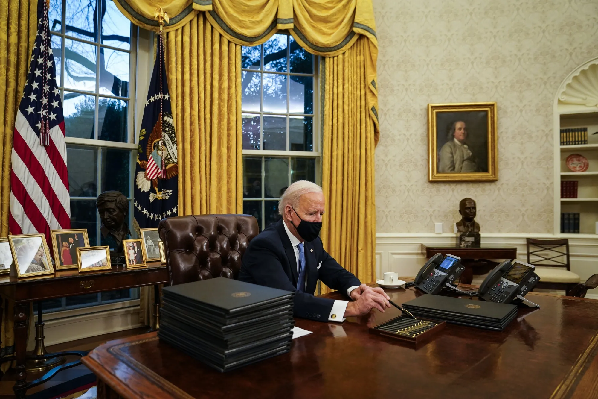 President Biden on inauguration day in the Oval Office, decorated with a newly hung portrait of Benjamin Franklin.