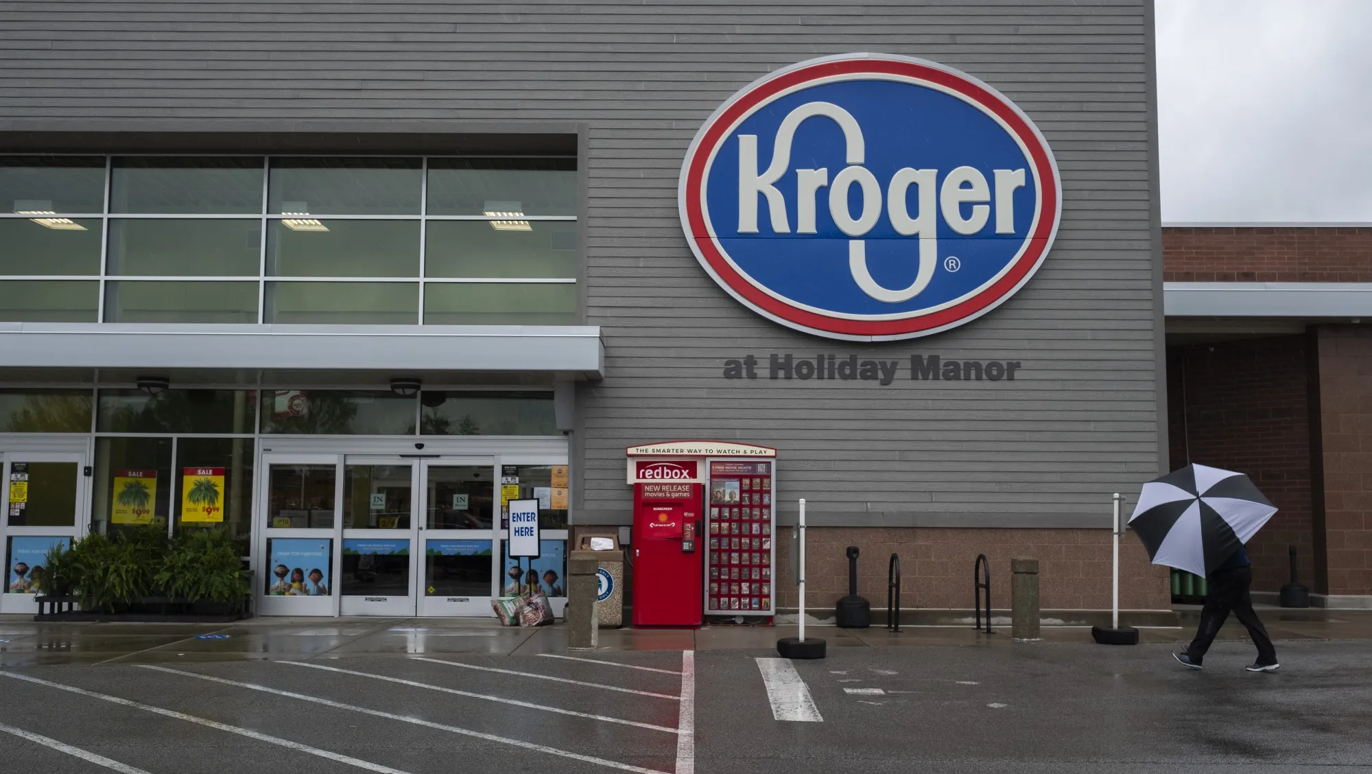 A shopper holding an umbrella walks towards a Kroger Co. grocery store in Louisville, Kentucky, on April 26.&nbsp;