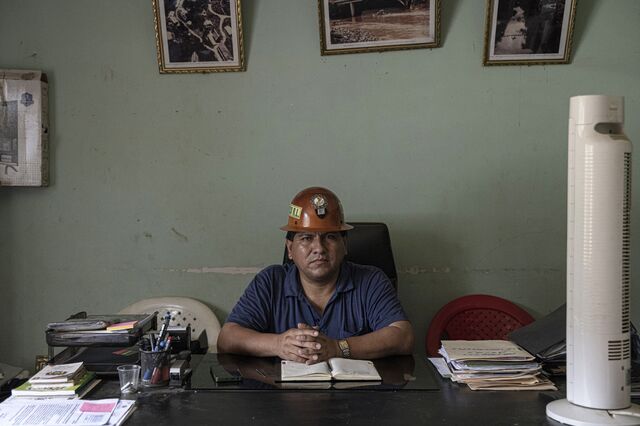 Cristobal Mamani  sits in his office wearing a mining helmet. 