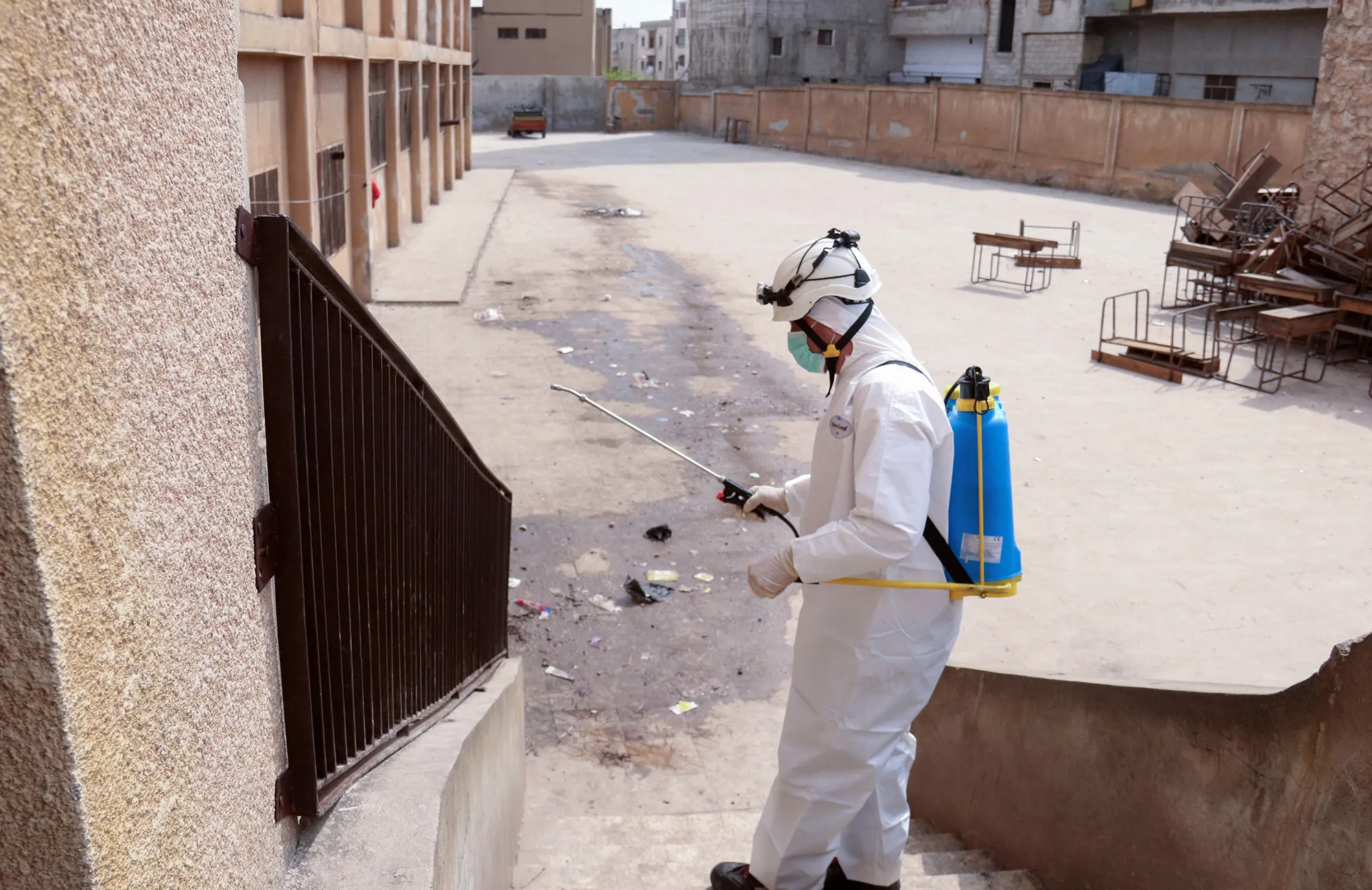 A member of the Syrian Civil Defence, also known as the "White Helmets", disinfects a school where displaced Syrians are sheltered in the town of Maaret Misrin, Syria's northwestern Idlib province, on March 25.