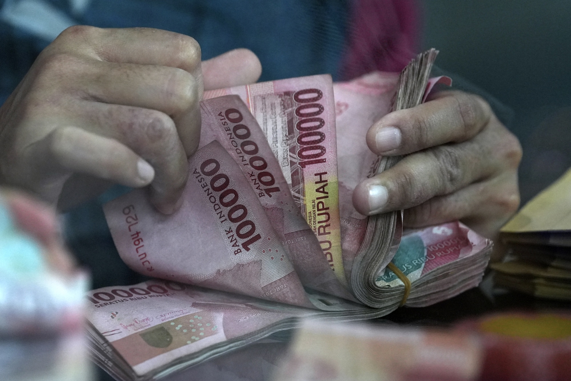 A worker counts rupiah banknotes at a currency exchange office in Jakarta.