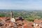 Church among red roofs of small italian town and green hills on background in Piedmont, Northern Italy.