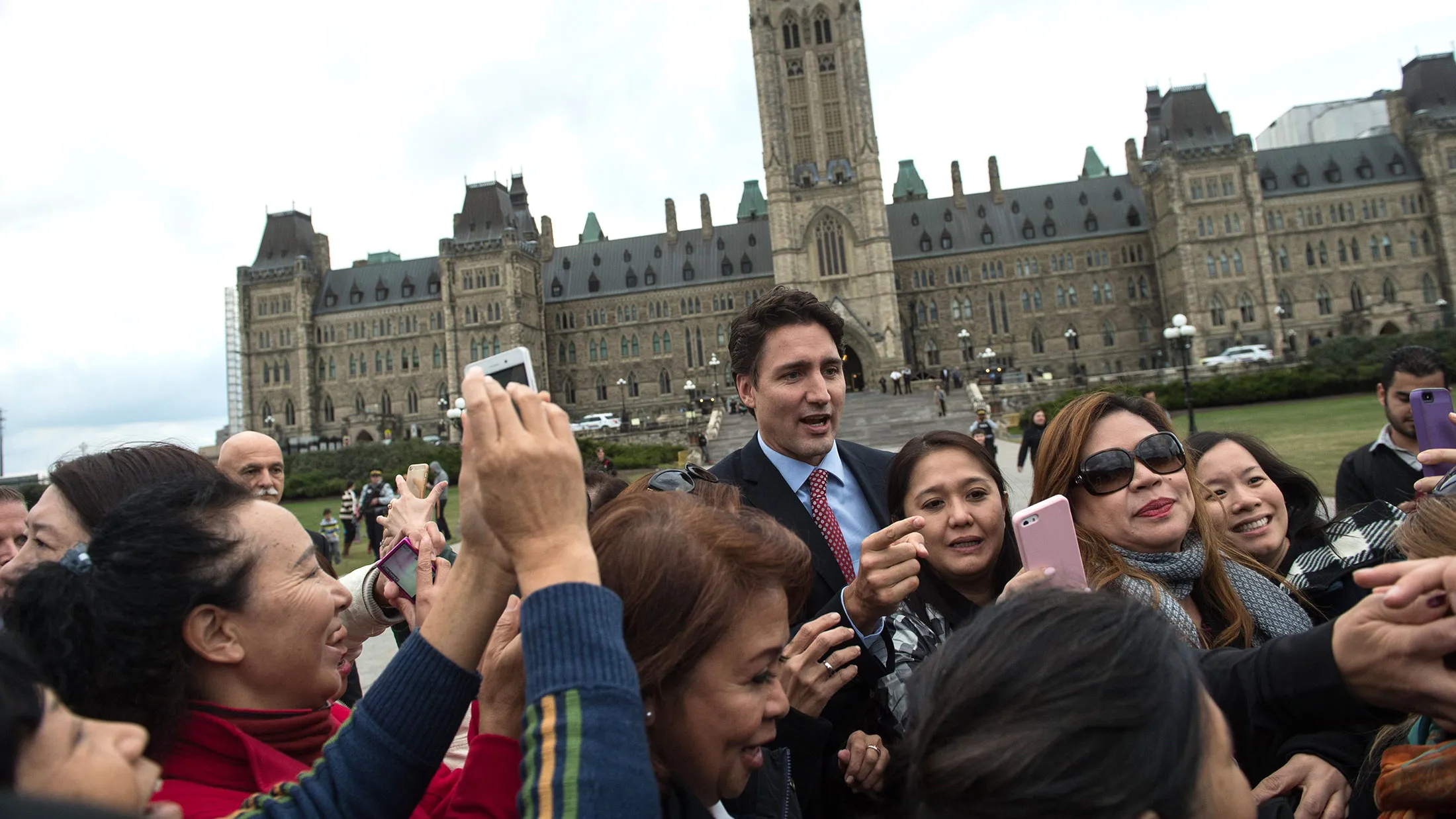 Canadian Liberal Party leader Justin Trudeau poses for photos with tourists as he walks from the parliament to give a press conference in Ottawa on Oct. 20, 2015 after winning the general elections.
