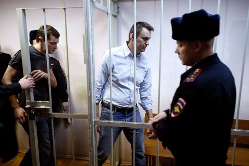 Russian opposition activist and anti-corruption crusader Alexei Navalny, 38, center, and his brother Oleg Navalny, left, enter into the cage at a court in Moscow last year.
