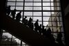 Attendees riding down an escalator are silhouetted during the South By Southwest (SXSW) conference in Austin, Texas, U.S., on Sunday, March 11, 2018. Amid the raucous parties and speed networking at the annual festival that draws people from technology, film, and music to Austin, Texas, there will be some soul searching about gender discrimination, sexual harassment and how to fix the broken workplace culture.