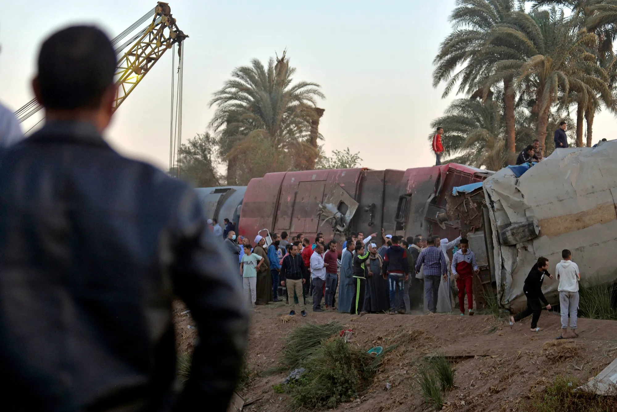 People gather around the wreckage of two trains that collided in the Tahta district of Sohag province, Egypt, on March 26.