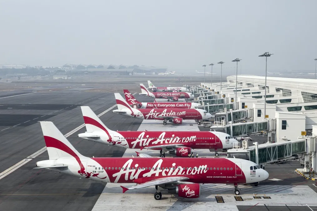 AirAsia Bhd. aircraft stand next to boarding gates at Kuala Lumpur International Airport.&nbsp;