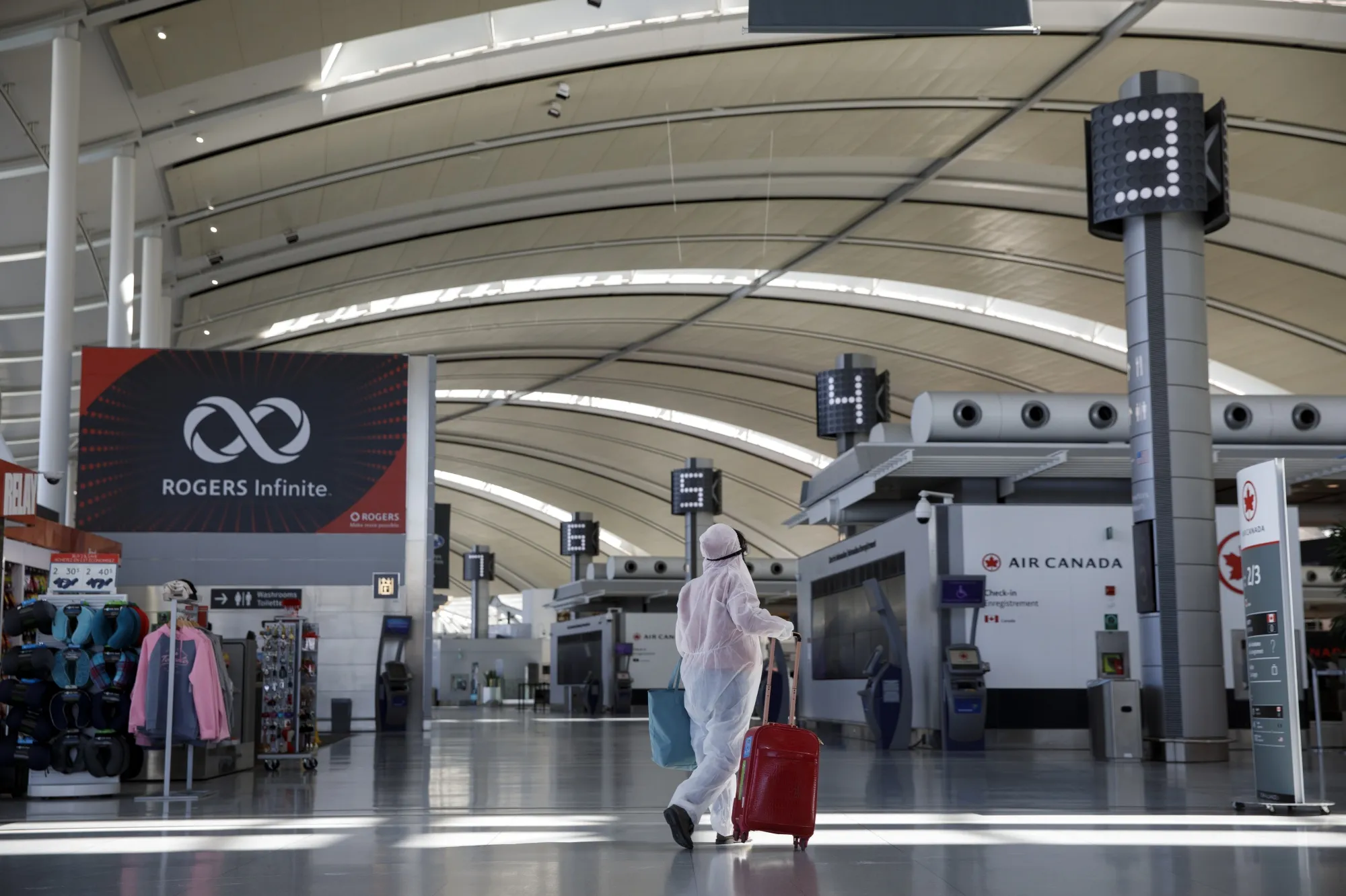 A traveler wearing a protective suit and mask walks through Pearson airport in Toronto on April 8, 2020.