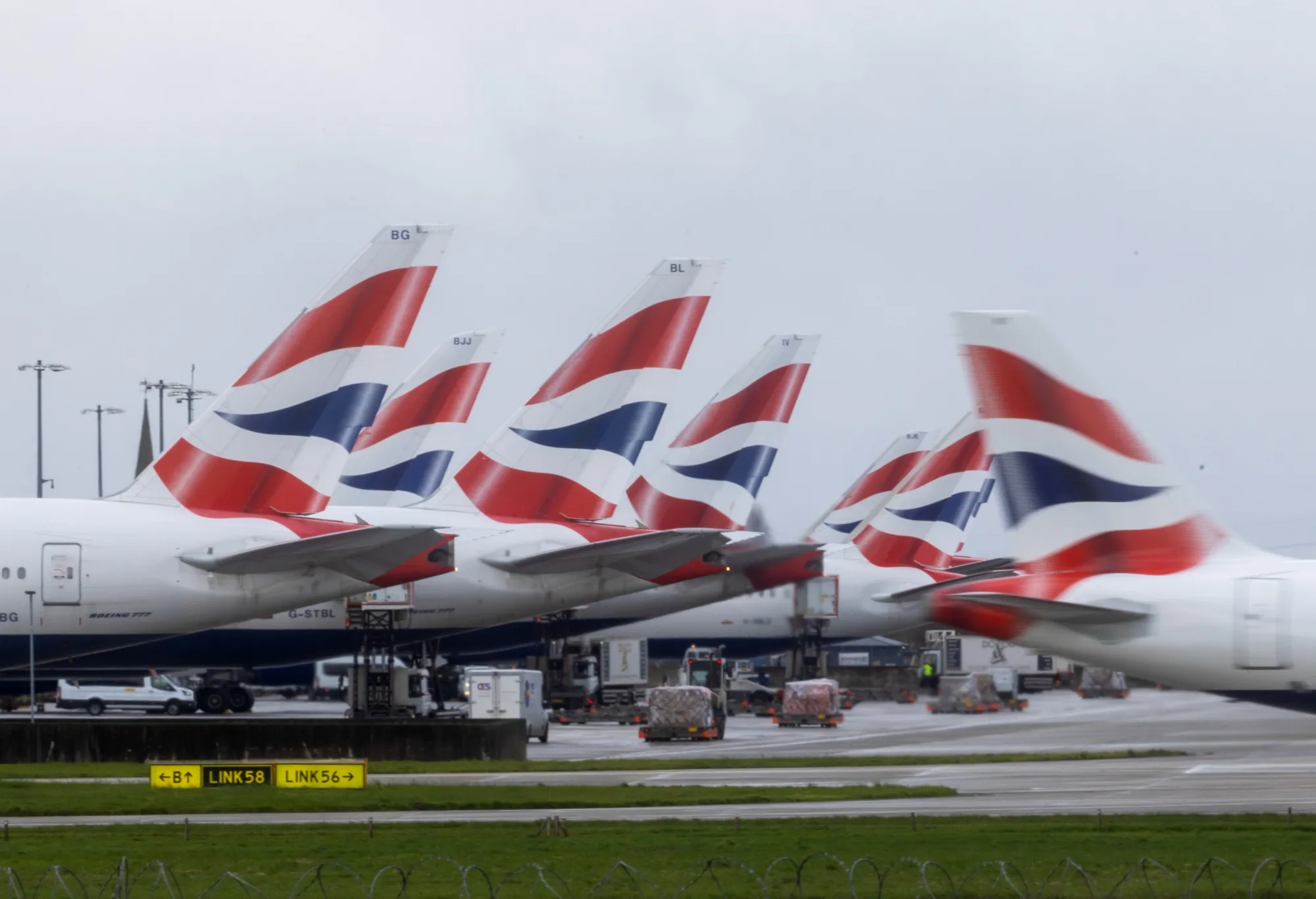 A passenger airplane, operated by British Airways, next to other airplanes on the tarmac at London Heathrow Airport in London, UK.