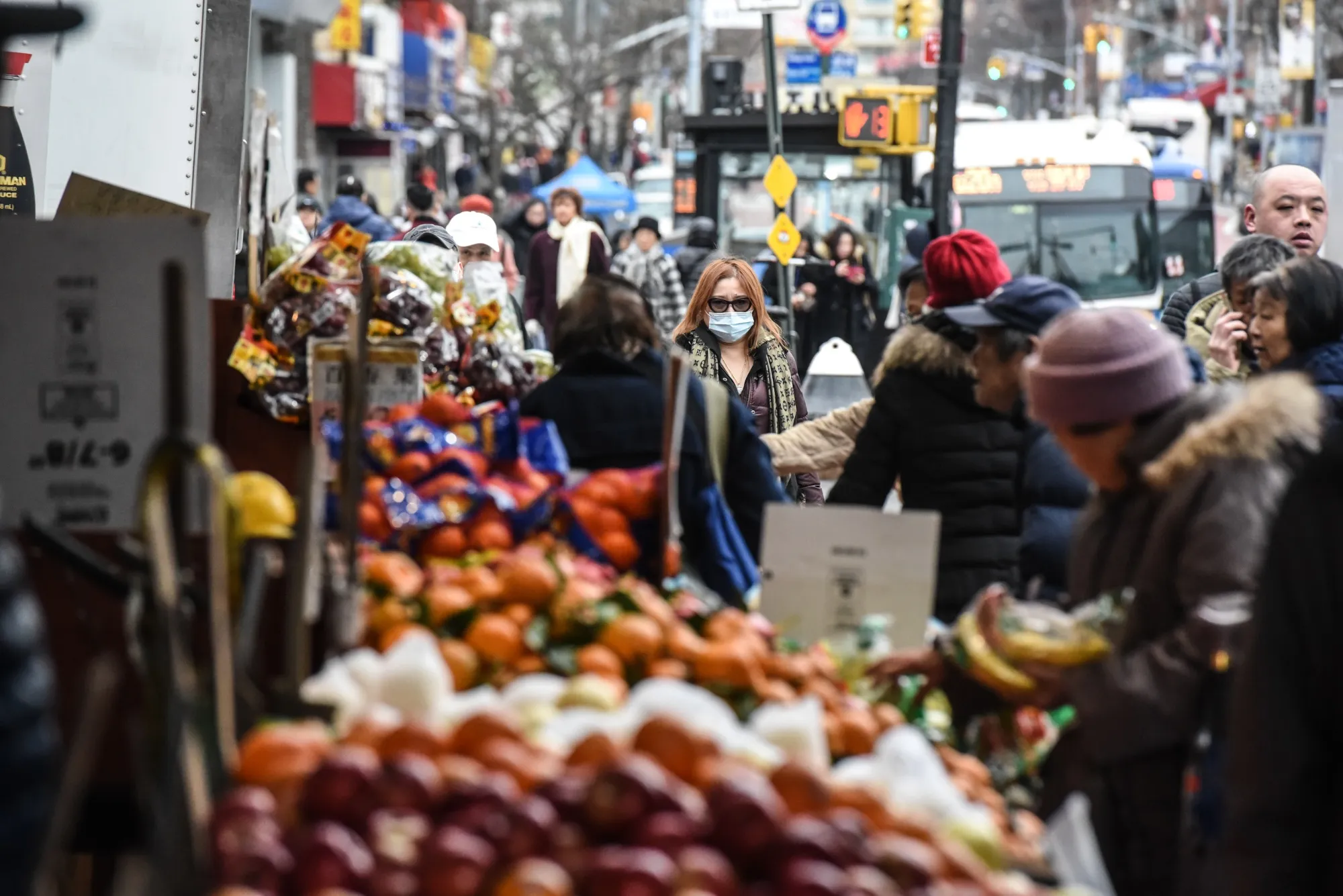A pedestrian wearing a face mask walks along a street in New York.