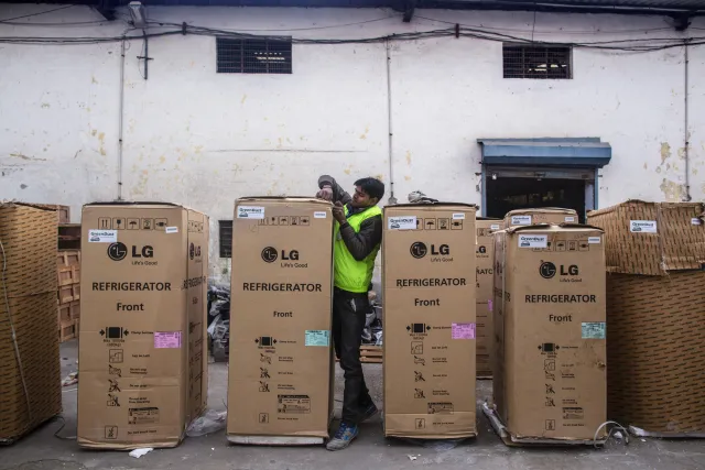 An employee secures the packaging of an LG Electronics Inc. refrigerator outside a warehouse&nbsp;in New Delhi.