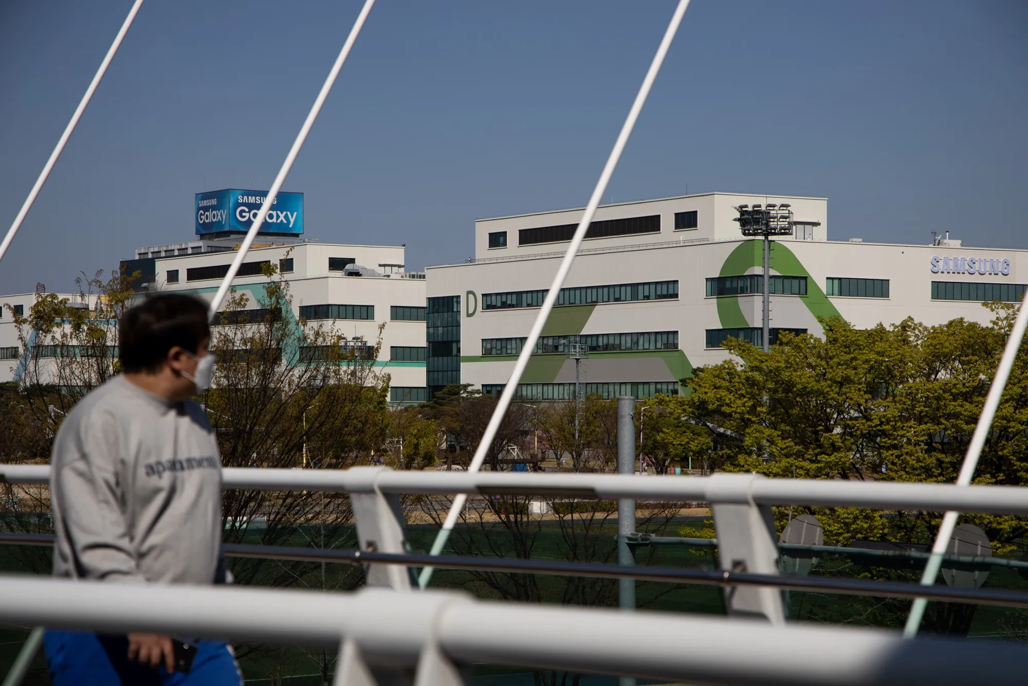 A man wearing a protective mask walks past the Samsung Electronics Co.'s smartphone manufacturing factory in Gumi, South Korea.&nbsp;
